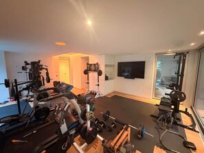 A home gym with exercise equipment, a large mirror, and a TV on the wall.