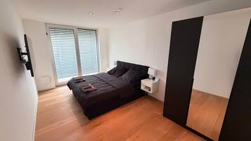 Un dormitorio con cama, mesita de noche y un espejo grande.