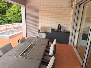 Een terras met een tafel, stoelen, een barbecue en uitzicht op groen.
