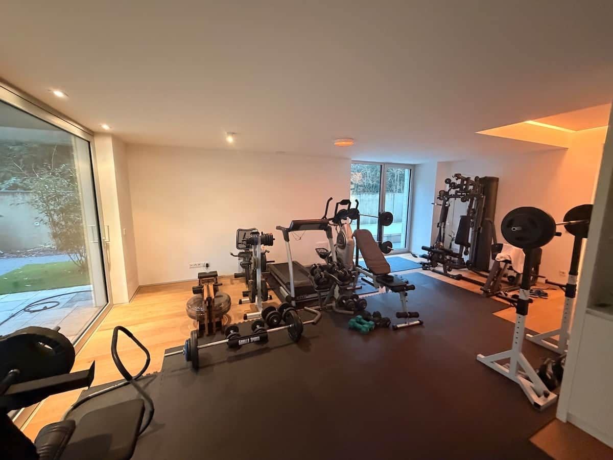A home gym with various exercise equipment, including a bench press, dumbbells, and weight machines.