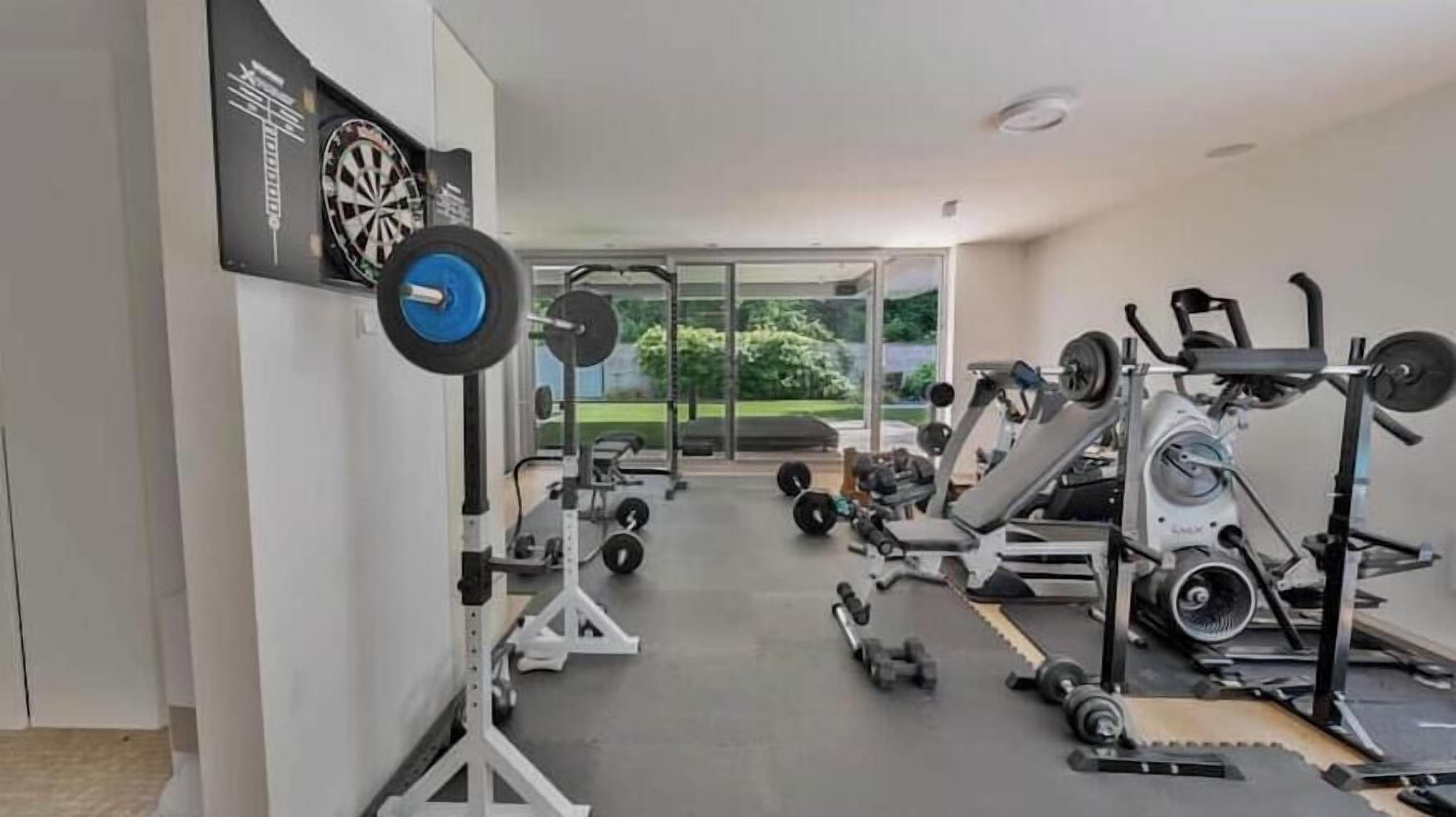 Ein Fitnessraum mit Trainingsgeräten, einer Gewichtbank und einer Spiegelwand.
