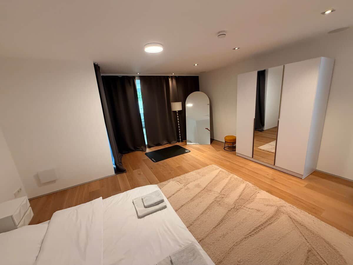 Een moderne slaapkamer met een bed, een grote spiegel en een kledingkast.