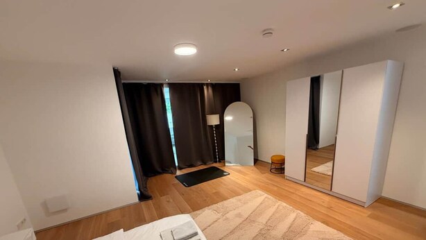 Une chambre à coucher moderne avec un lit, un grand miroir et une armoire.