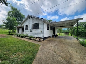 A single-story house with a covered porch, a concrete driveway, and a grassy yard. - Tranquil 3-bedroom Mountain View Farmhouse in Charming Greeneville (Greeneville)
