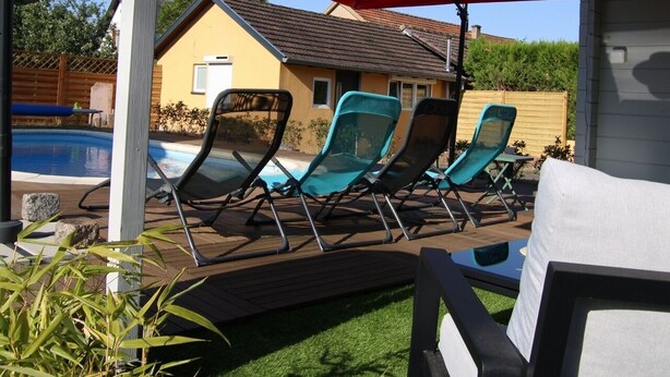 Ein Poolbereich mit Liegestühlen, Sonnenschirmen und einem Haus im Hintergrund.