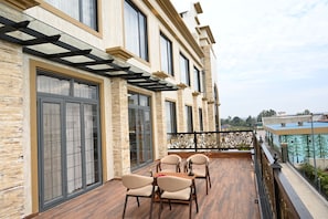 A balcony with a wooden floor, a glass railing, and a table with chairs.