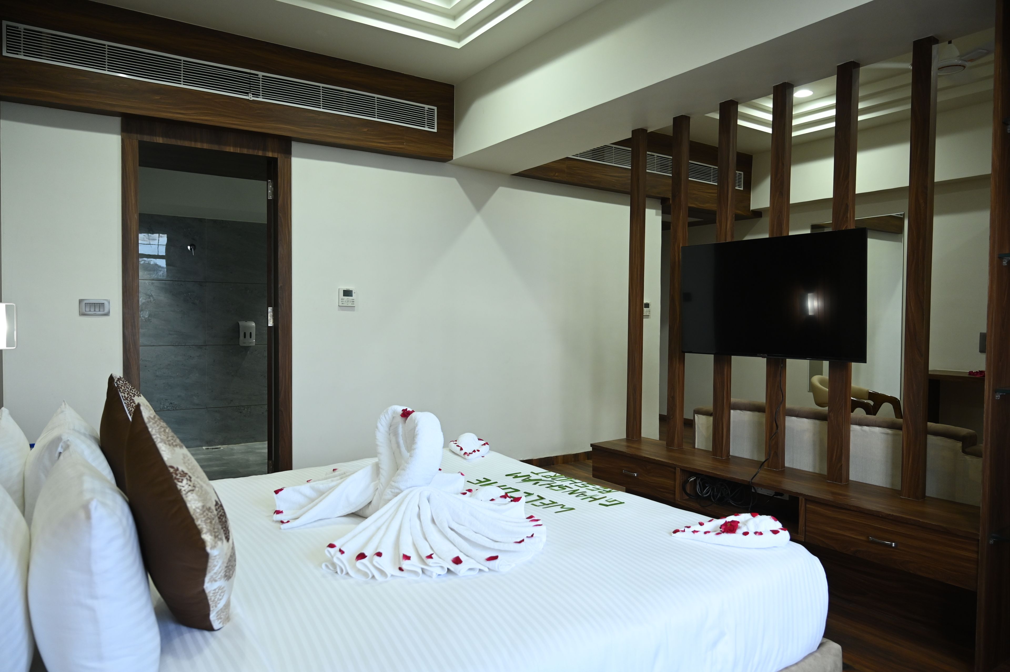 Habitación de hotel con cama, televisión y pared de paneles de madera.