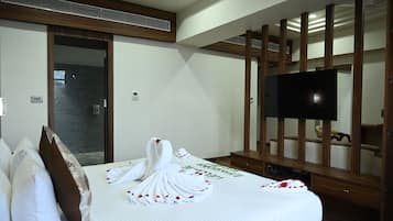 Habitación de hotel con cama, televisión y pared de paneles de madera.