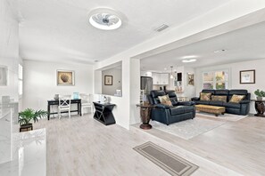 Ein modernes Wohnzimmer mit einer schwarzen Ledersofa, einem Essbereich mit schwarzem Tisch und einer Küche im Hintergrund.