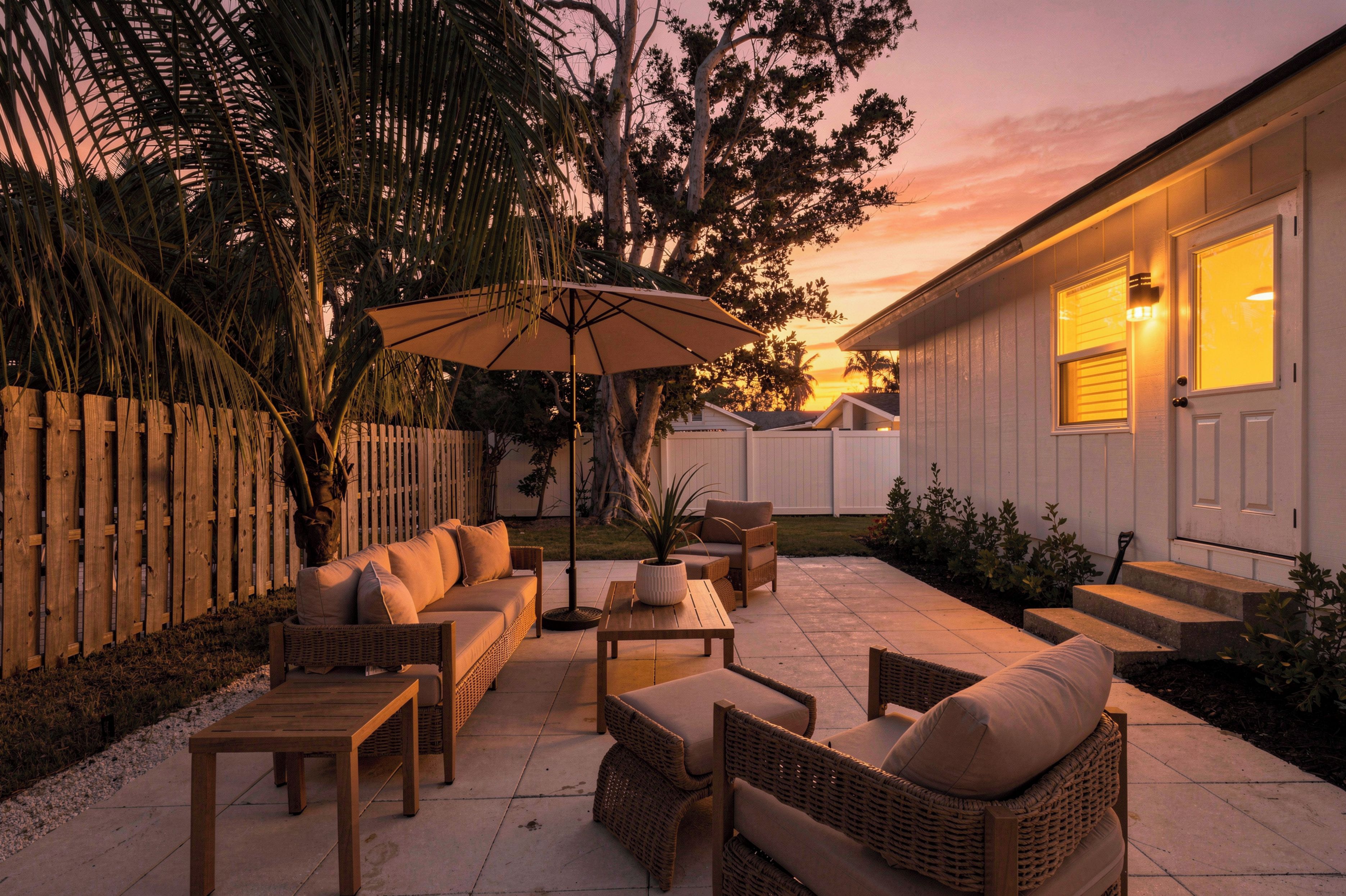A patio with outdoor furniture, a wooden fence, and a house in the background.