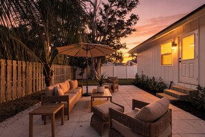 Une terrasse avec des meubles d’extérieur, une clôture en bois et une maison en arrière-plan.