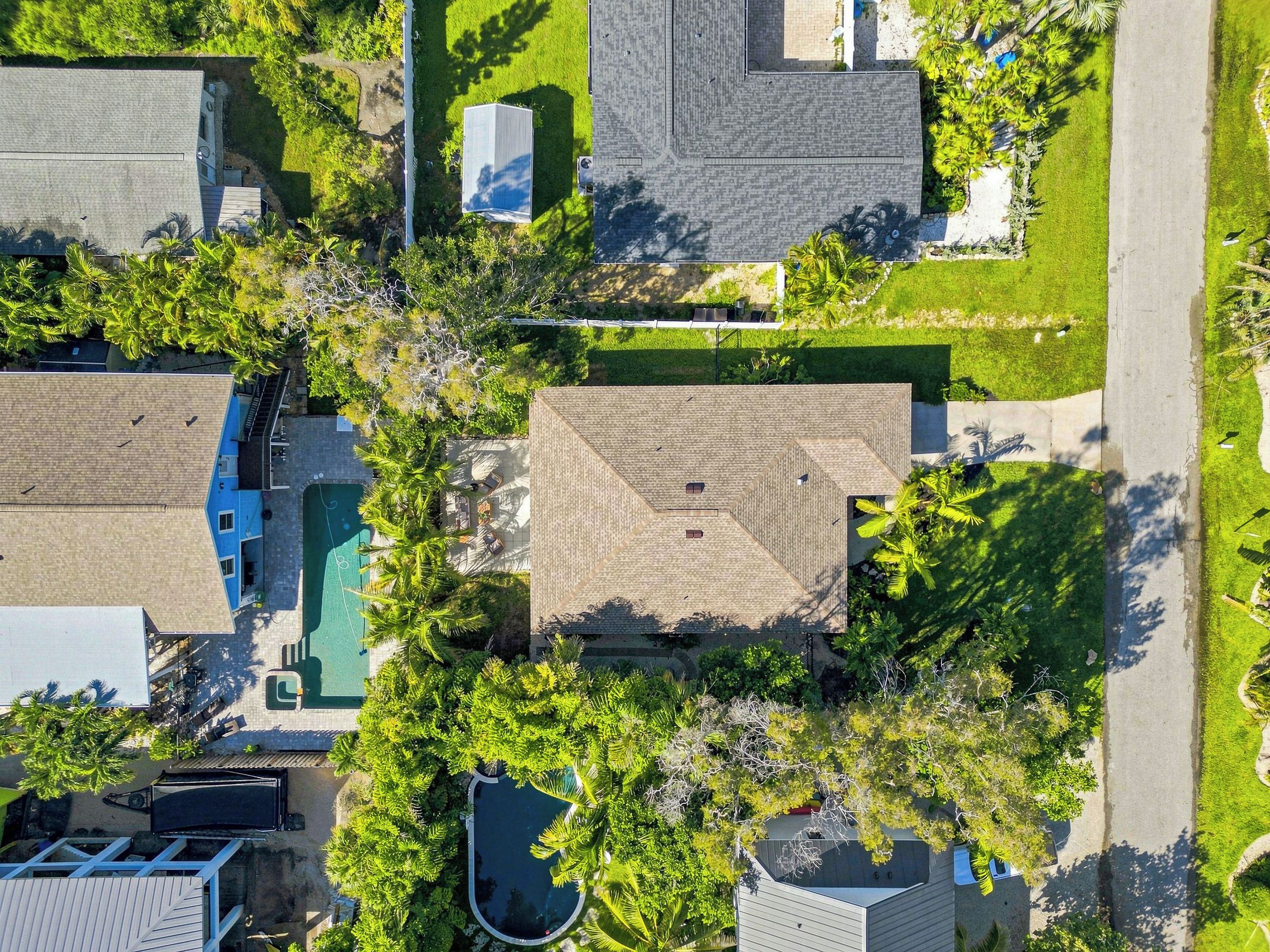 Vue aérienne d’un quartier résidentiel avec de nombreuses maisons, une piscine et une végétation luxuriante.