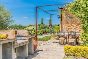 Un patio al aire libre con una parrilla de ladrillo, pared de piedra y mobiliario exterior.