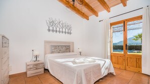 Un dormitorio con cama, mesita de noche, una obra de arte en la pared y ventana con vistas.