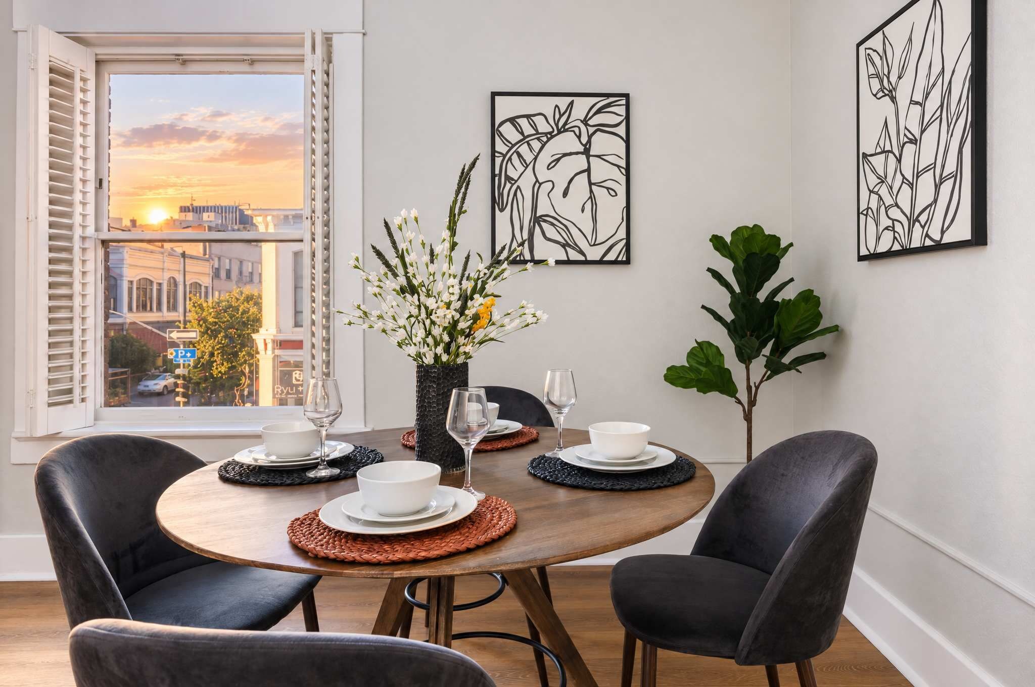 A dining area with a round table set for four, surrounded by dark chairs.