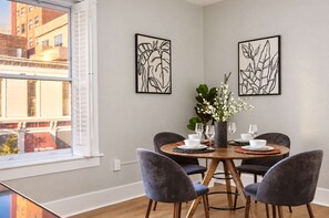 Un coin repas comprenant une table ronde, quatre chaises et deux œuvres d’art accrochées au mur.
