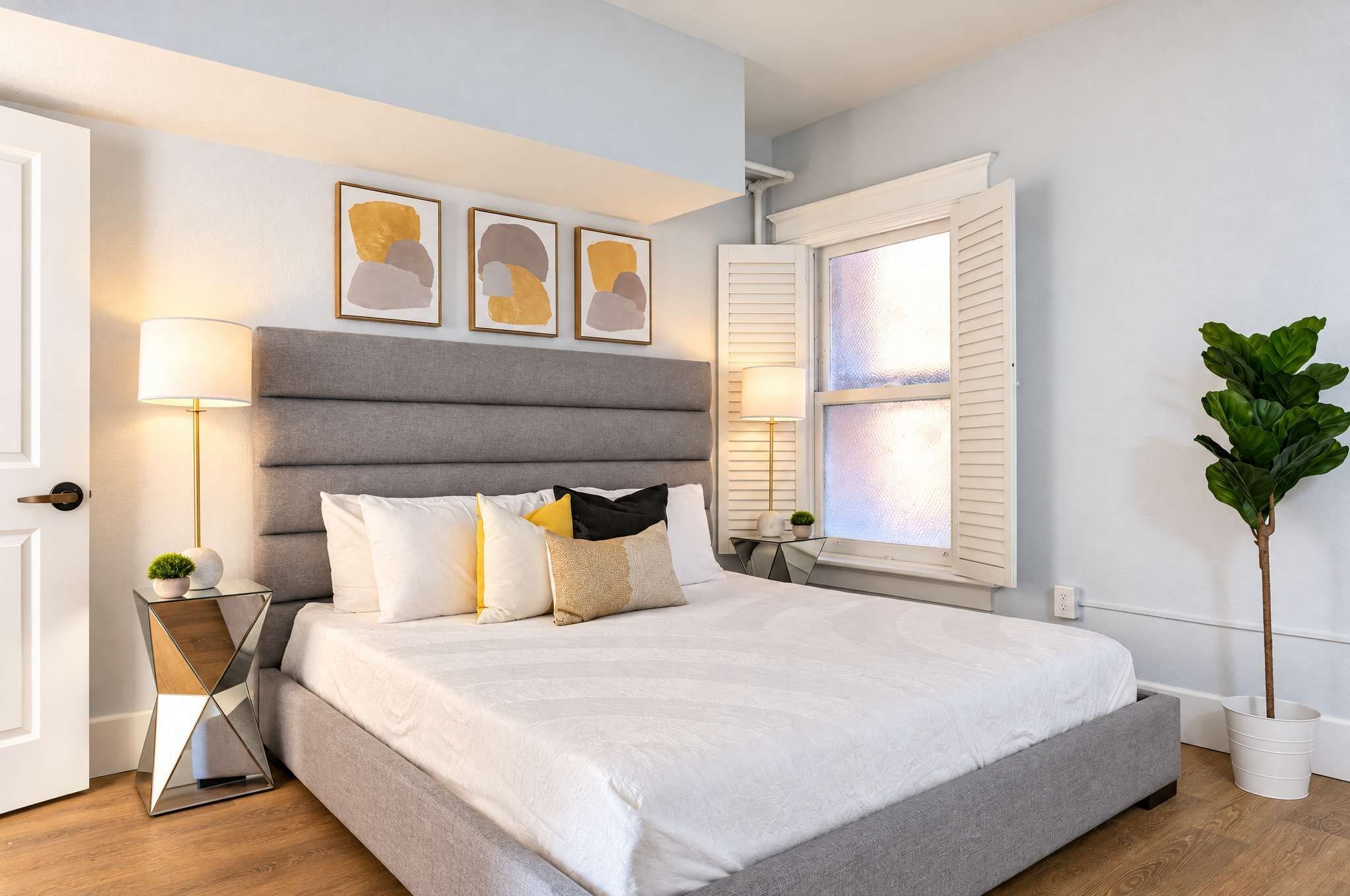 A modern bedroom with a large bed, bedside lamps, and abstract wall art.