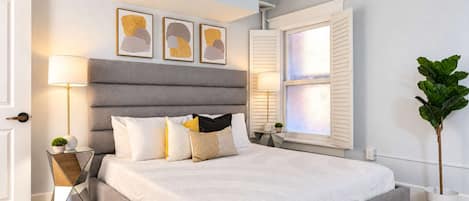 Un dormitorio moderno con una cama grande, lámparas de noche y arte abstracto en la pared.