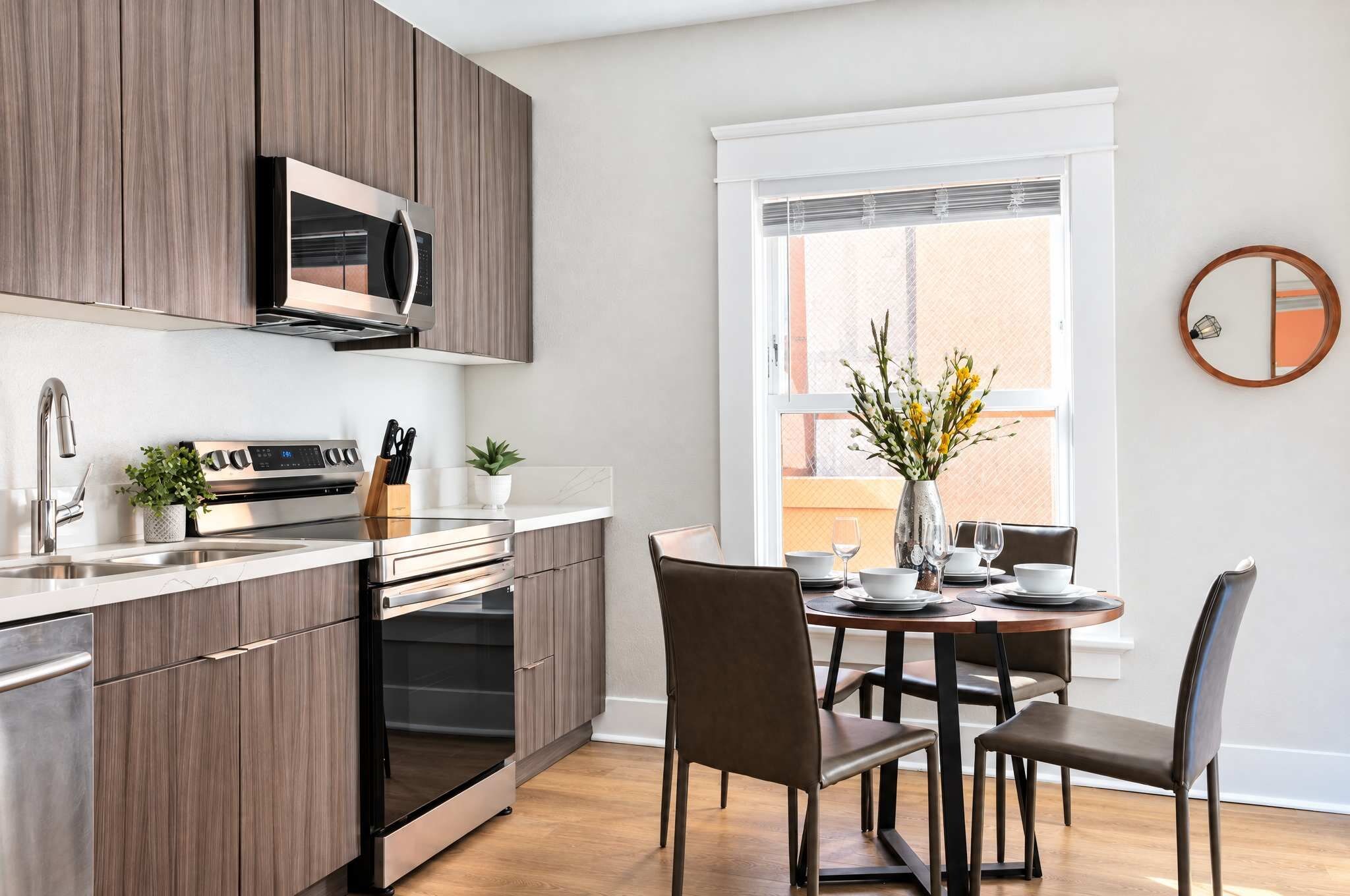 Una cocina moderna con electrodomésticos integrados, un comedor con mesa y sillas, y un ventanal con vistas.