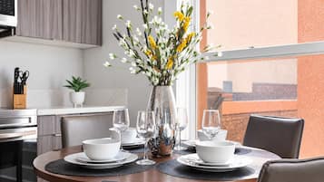 Una mesa de comedor dispuesta con cuencos blancos, copas de vino y un florero con flores.