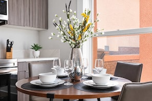 A dining table set with white bowls, wine glasses, and a vase with flowers. - The Penn Hotel - Smart TV, AC & Walk to Gaslamp!!! (San Diego)