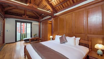 A hotel room with a large bed, wooden headboard, and a balcony with a view of buildings.