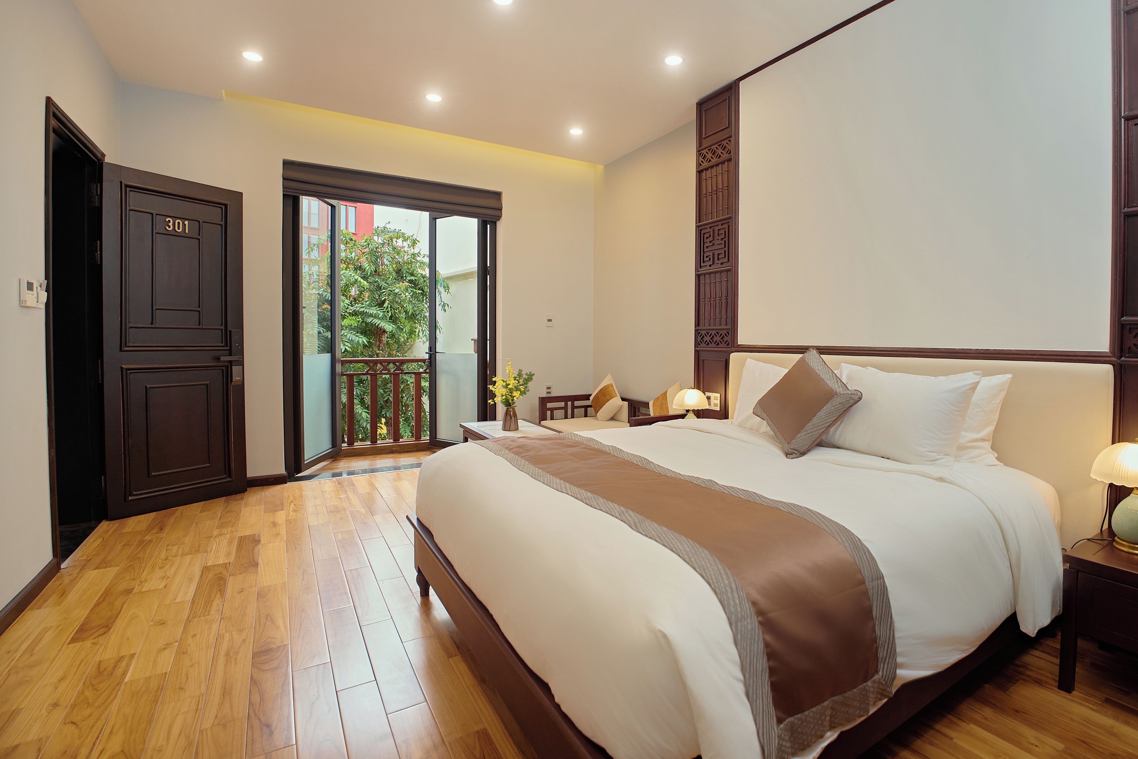 Una habitación de hotel con una cama grande, un balcón y suelo de madera.