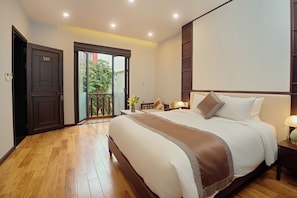 Una habitación de hotel con una cama grande, un balcón y suelo de madera.