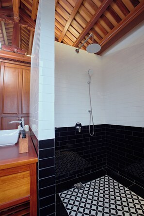 A bathroom with a wooden vanity, a white sink, a shower with a black and white patterned floor, and a wooden ceiling. - Thong Dong Quan Boutique Hotel Hue (Thuan Hoa)