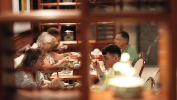 Un grupo de personas cenando en una mesa con vista a una estantería al fondo.