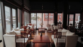 A spacious room with large windows, wooden furniture, and a view of buildings outside.