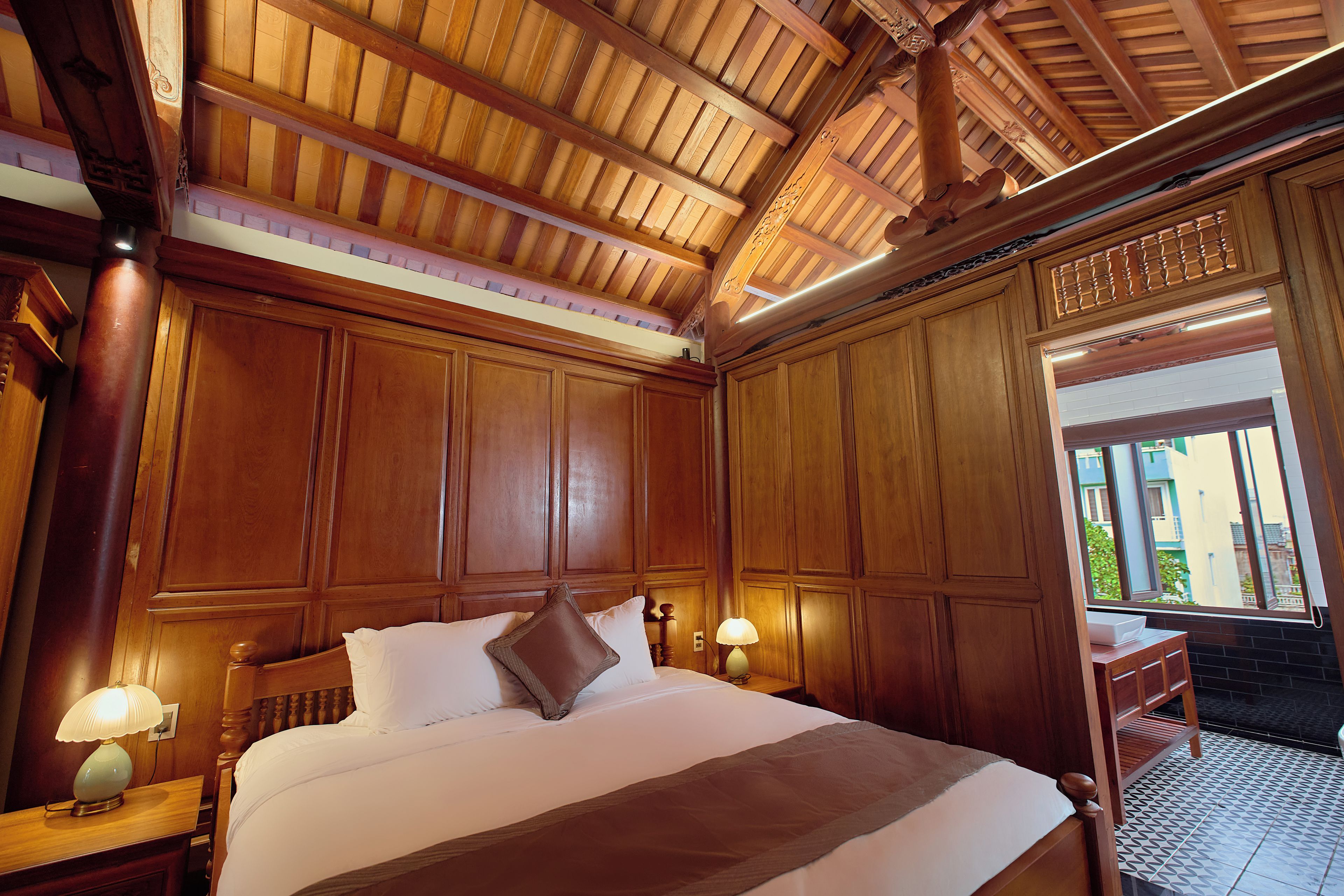 Una habitación con paneles de madera, una cama, mesitas de noche y un ventanal.