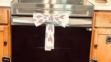 Forno in acciaio inox con pannello di controllo digitale, schienale della cucina rivestito con mosaico e pensili con etichette.
