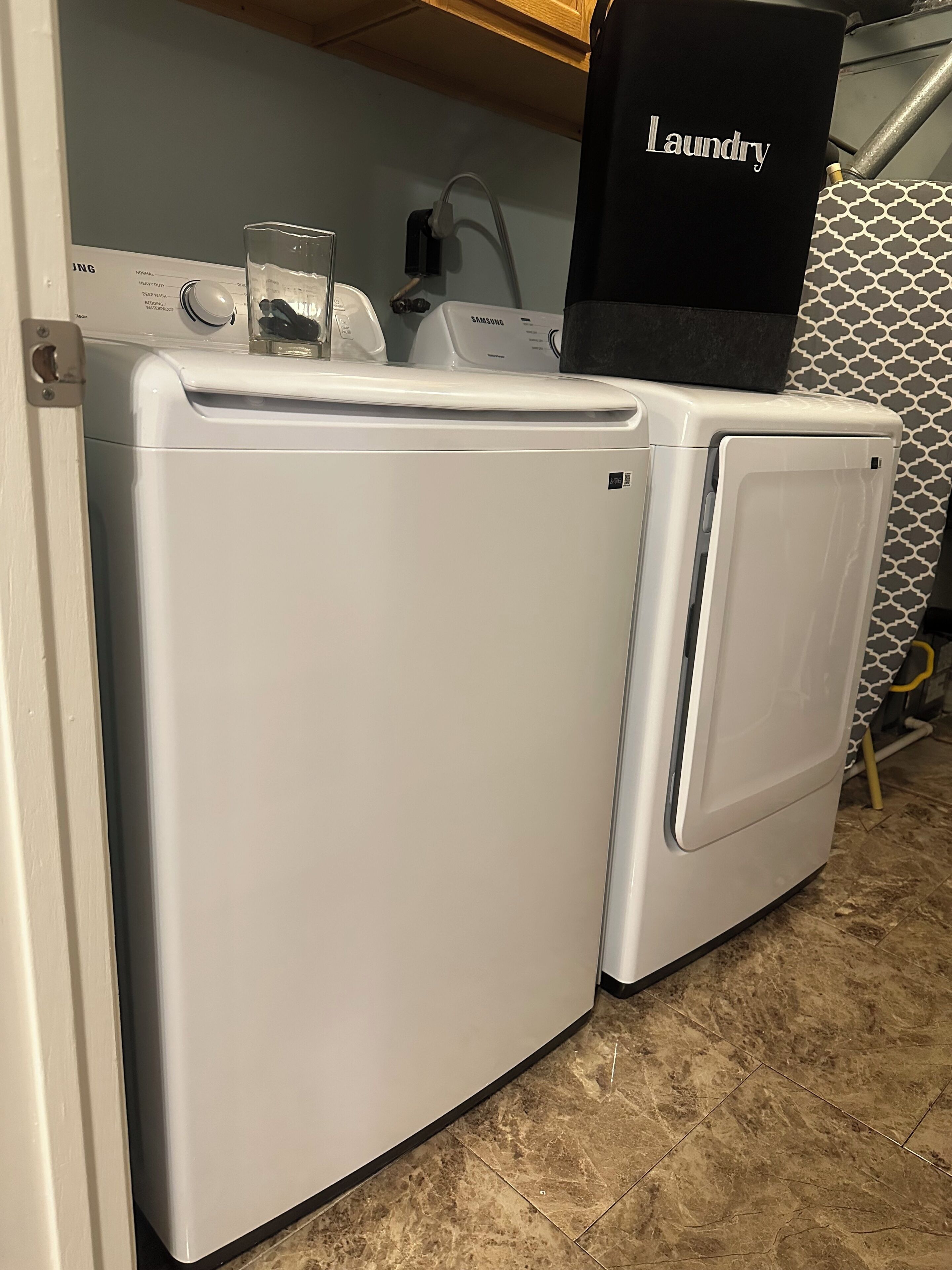 Une machine à laver et un sèche-linge à chargement frontal, placés côte à côte dans une buanderie.