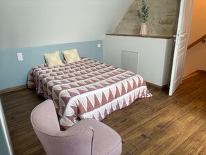 Ein Schlafzimmer mit einem Bett, einem Sessel und Holzboden.
