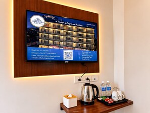 Habitación de hotel con televisor de pantalla plana montado en la pared, mostrando el sitio web del Buddha Heritage Hotel.