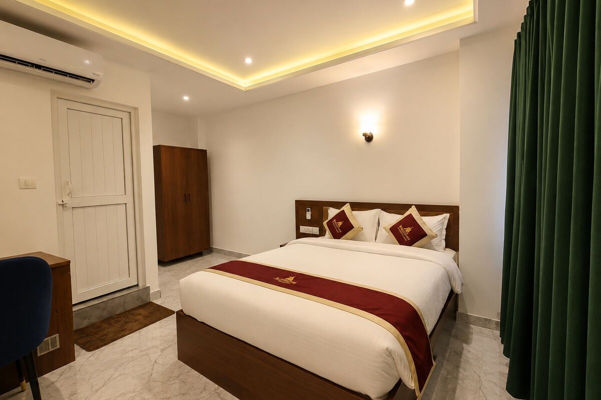 A hotel room with a large bed, a wardrobe, a desk, and a green curtain.
