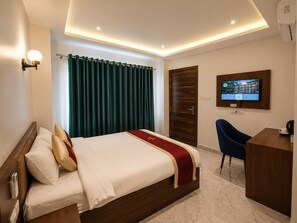 A hotel room with a bed, a desk, a television, and a window with curtains. - Buddha Heritage Hotel (Siddharthanagar)