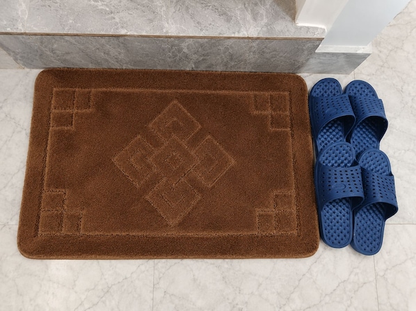 A brown textured mat with a diamond pattern and a pair of blue slip-on slippers.