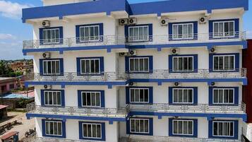 Un hotel de varios pisos con piscina, balcones y cielo despejado.
