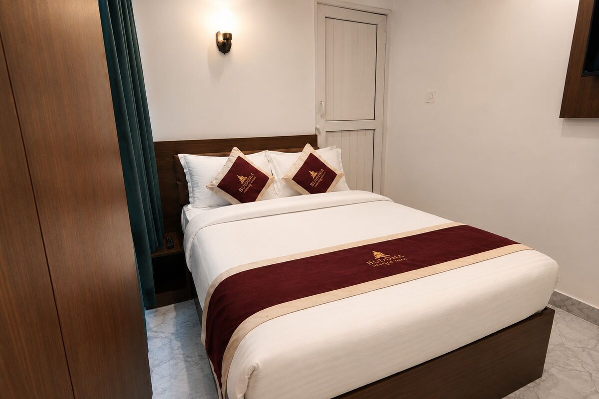 A hotel room with a large bed, a wooden headboard, a wall-mounted light, and a door.