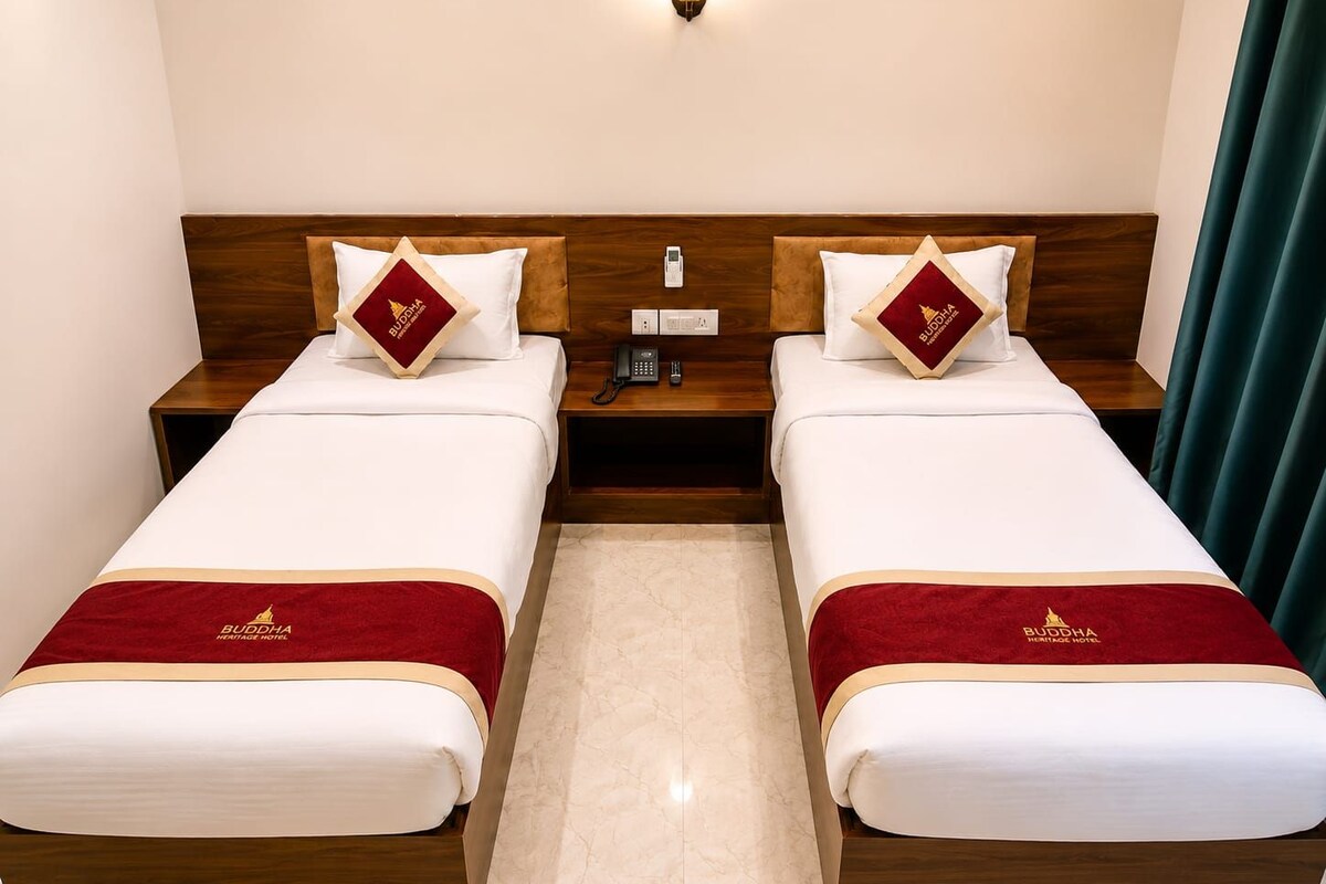 A hotel room with two beds, each with a red and white bedspread, a wooden headboard, and a pillow with a logo.