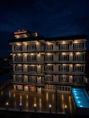 A multi-story hotel with balconies and a swimming pool.