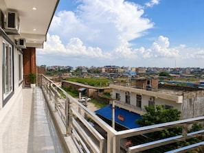 A balcony with a view of a cityscape, including buildings and a Coca-Cola sign.