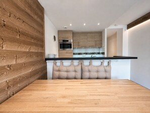 Eine moderne Küche mit Holzschränken, einer schwarzen Arbeitsplatte und einer zentralen Kochinsel mit Sitzbank.