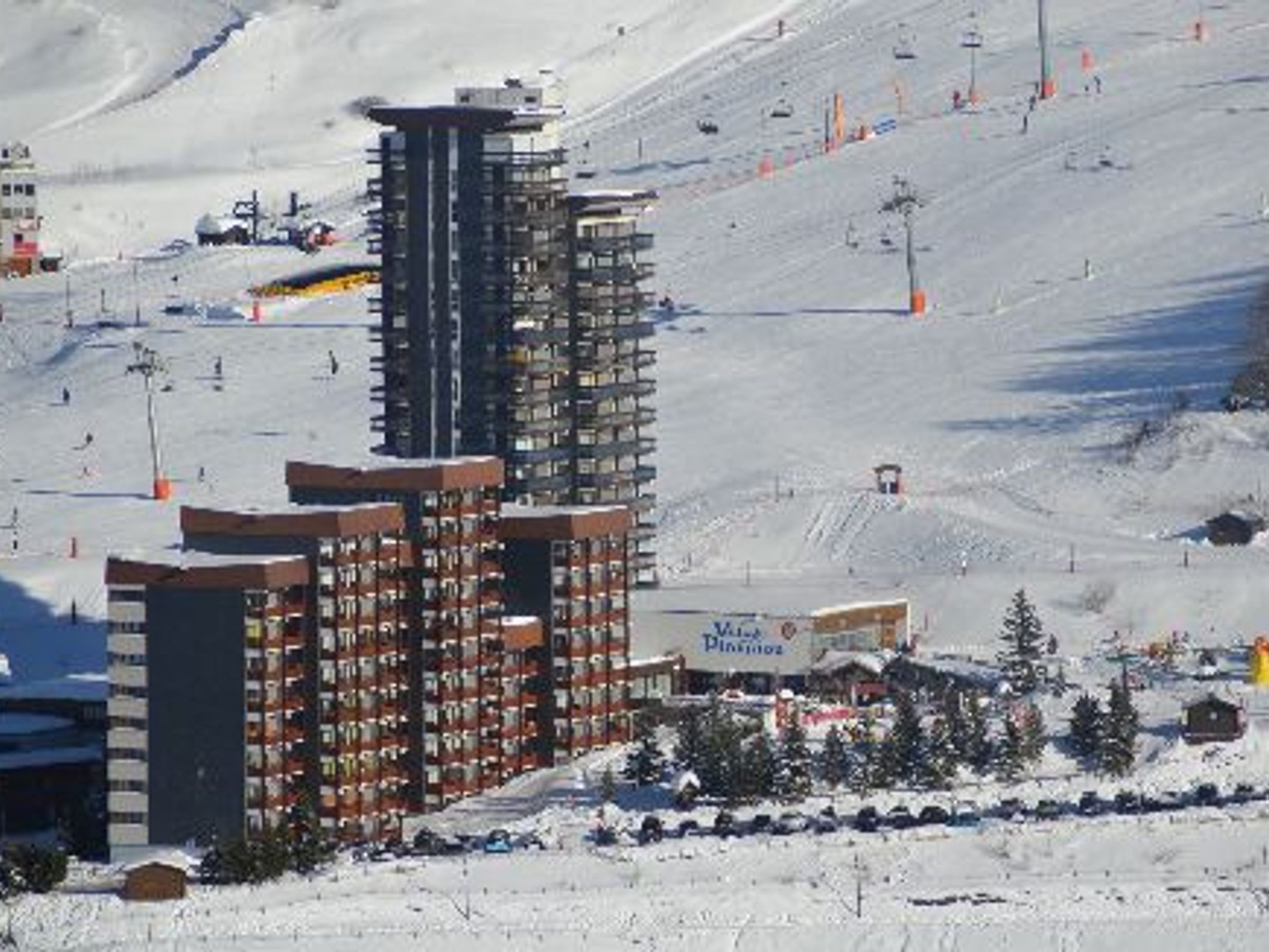 Une station de ski avec un grand bâtiment, des remontées mécaniques et une piste enneigée.