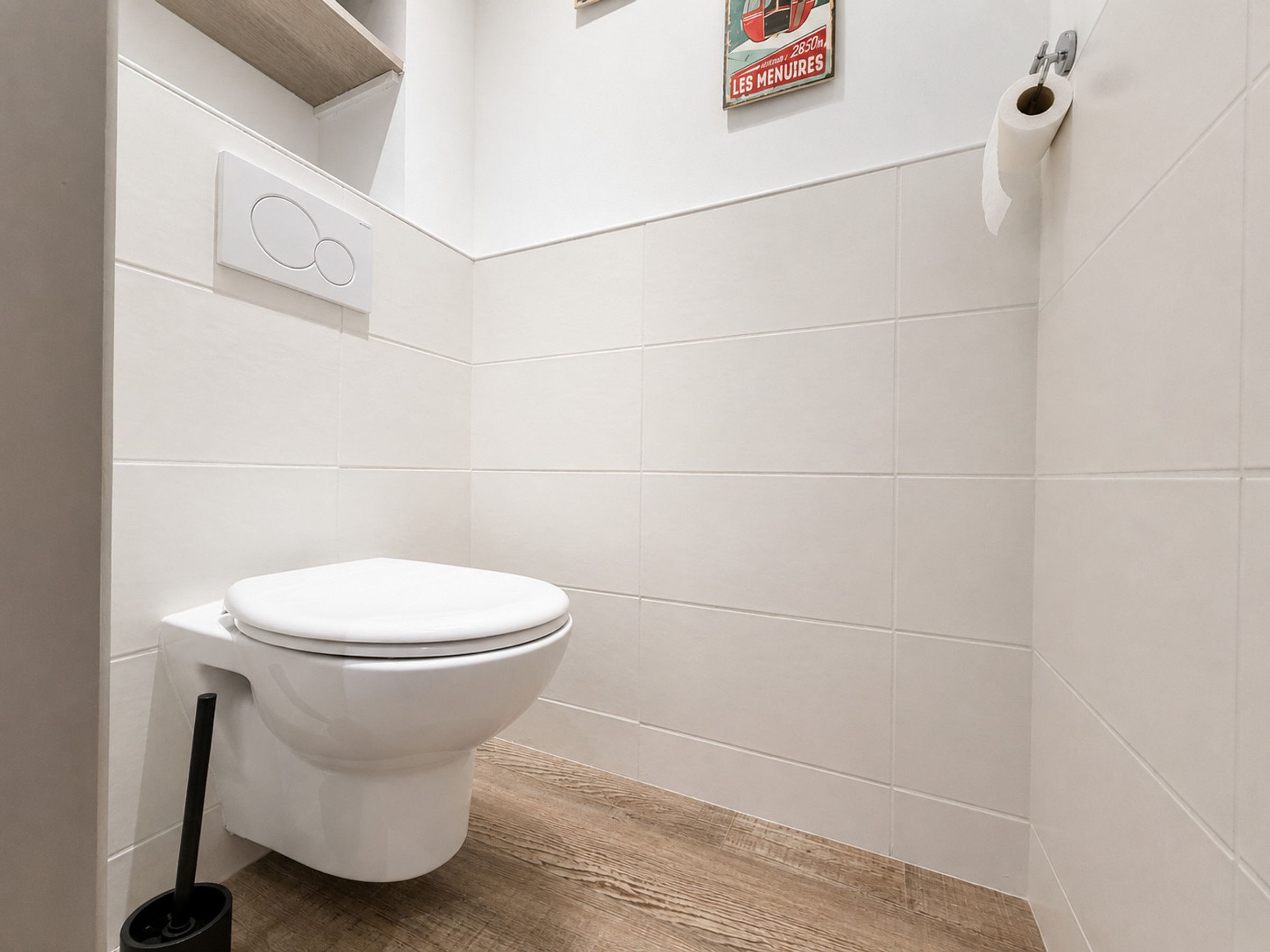 A modern bathroom with a white toilet, a wooden floor, and a wall-mounted toilet paper holder.