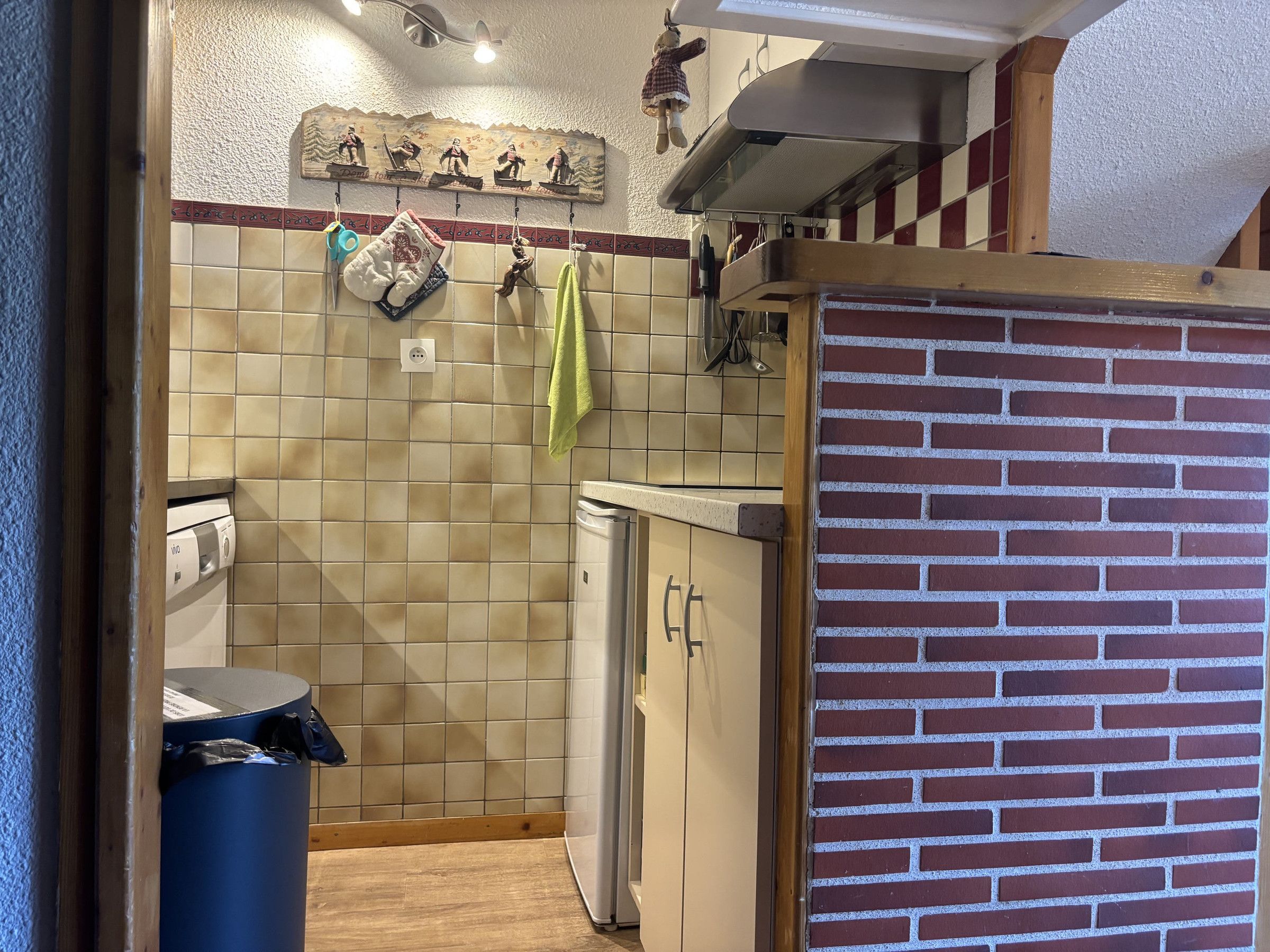 Een keuken met een betegelde spatwand, een handdoek aan de haak en een bakstenen muur.