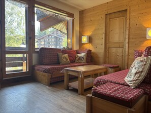 A cozy room with a wooden floor, a sofa set, a table, and a door. - Duplex with valley view - 10 guests (La Plagne Montchavin Les Coches)