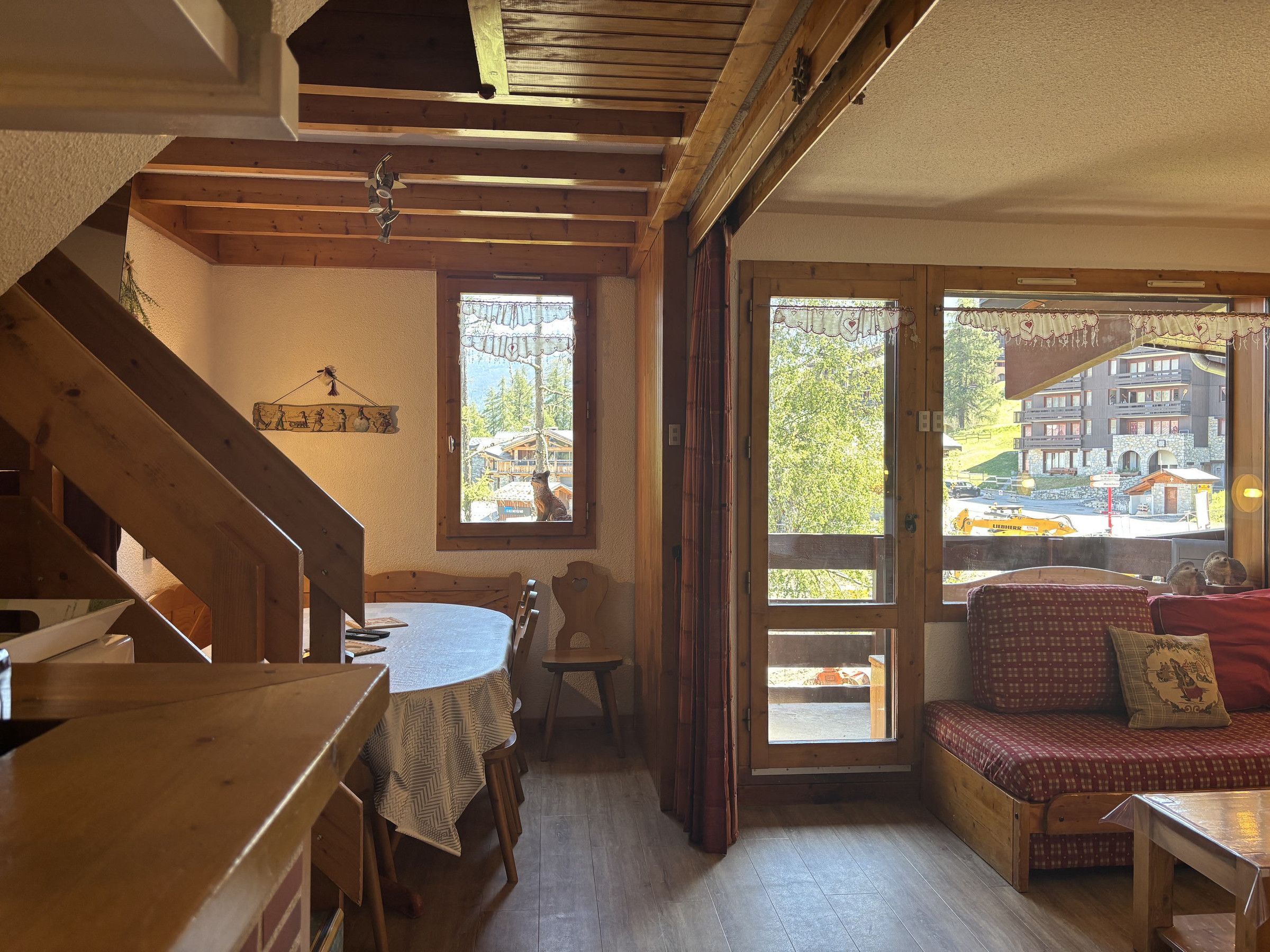 A wooden interior with a dining table, chairs, a bench, and a staircase.